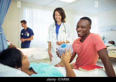 Man giving girlfriend present in hospital Stock Photo