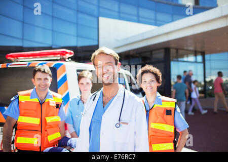 Doctor smiling with paramedics in hospital parking lot Stock Photo