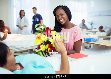 Woman giving mother bouquet of flowers in hospital Stock Photo