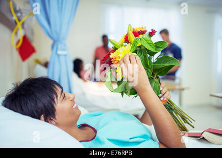 Patient admiring bouquet of flowers in hospital room Stock Photo
