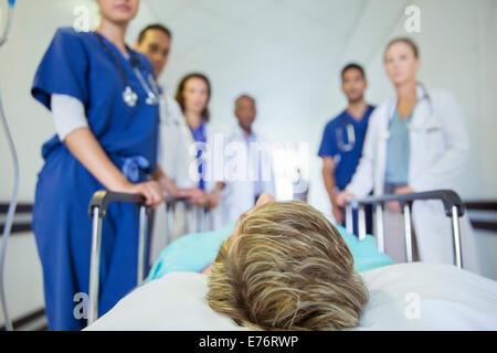 Doctors and nurses wheeling patient in hospital hallway Stock Photo