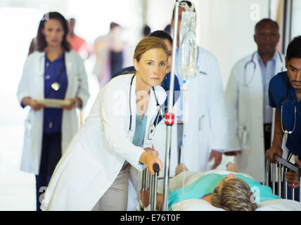 Doctors and nurses wheeling patient in hospital hallway Stock Photo