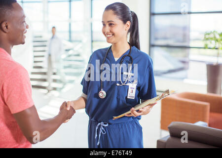 Nurse and patient shaking hands in hospital Stock Photo