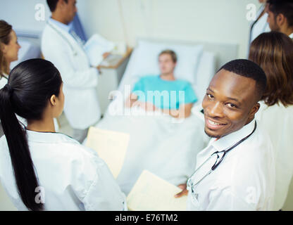 Doctor standing with residents in hospital room Stock Photo