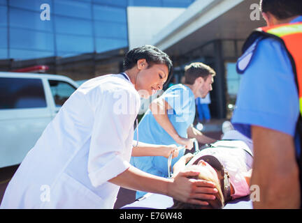 Doctor, nurse and paramedics wheeling patient to hospital Stock Photo