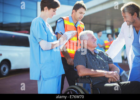 Doctor, nurse and paramedic talking to patient outside hospital Stock Photo