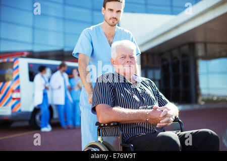Nurse wheeling patient outside hospital Stock Photo