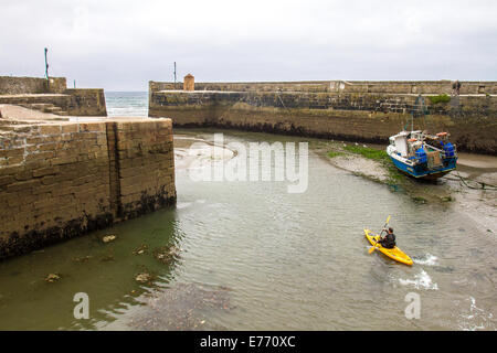 A canoeist paddling out of the harbour of Charlestown, a village and port on the south coast of Cornwall, England UK Stock Photo