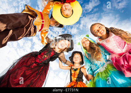 Many kids look down in circle wearing costumes Stock Photo