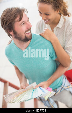 Couple hugging while observing color swatches together Stock Photo