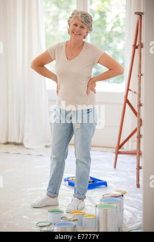 Older woman standing near paint in living space Stock Photo