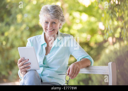 Older woman using digital tablet outdoors Stock Photo