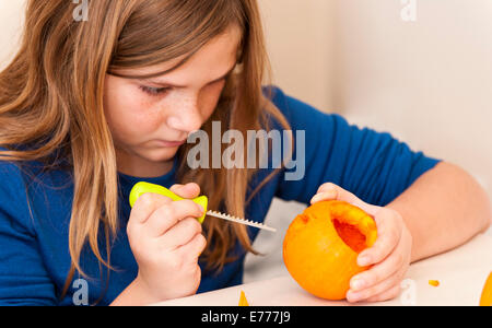 Girl focuses while carving a pumpkin for Halloween Stock Photo