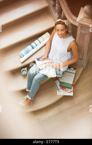 Woman sitting on stairs looking through color swatches Stock Photo