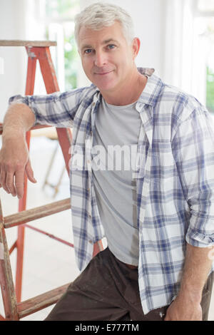 Older man leaning on ladder Stock Photo