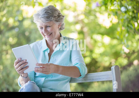 Older woman using digital tablet outdoors Stock Photo