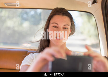 Woman in car taking picture with cell phone Stock Photo