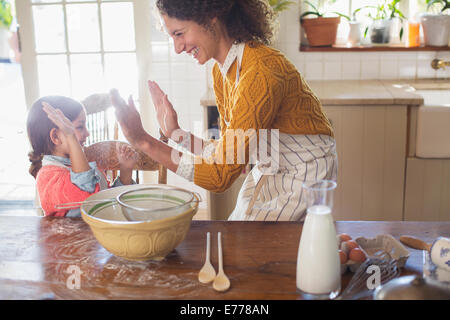 Mother and daughter high fiving in the kitchen Stock Photo
