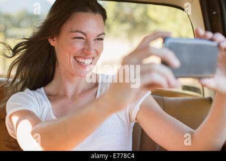 Woman riding in car taking picture with cell phone Stock Photo