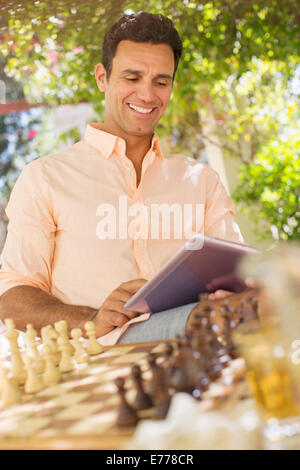 Man using digital tablet outdoors near chess game Stock Photo
