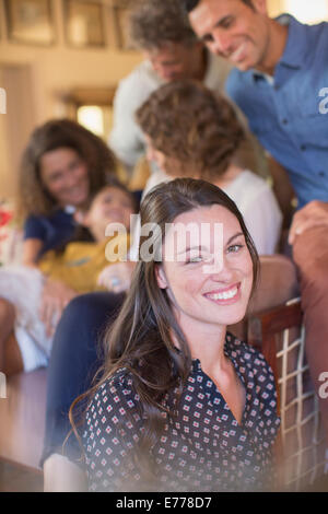 Woman smiling in living space with family Stock Photo