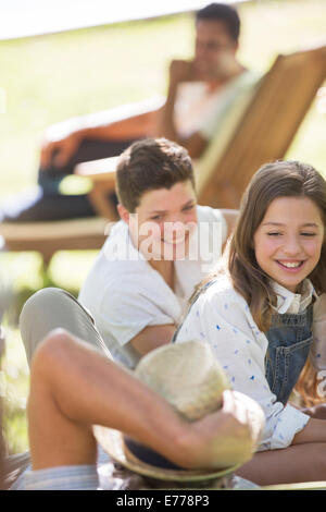 Grandchildren relaxing with Grandfather outdoors Stock Photo