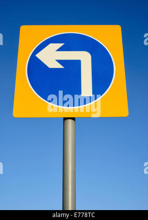 Turn left road sign set against a blue sky Stock Photo