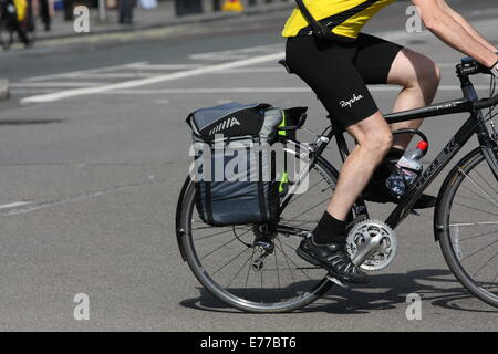 A cyclist riding along a road with panniers on his rear wheel Stock Photo
