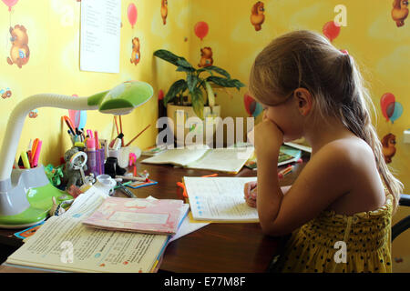 schoolgirl learns lessons at the table in her room Stock Photo