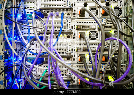 Tangle of ethernet and power cables plugged into the back of a computer server machine at a data center Stock Photo