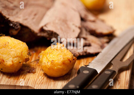 macro picture of roast potatoes and lamb on the chopping board Stock Photo