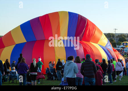 A crowd watches as a rainbow colored hot air balloon is inflated in Colorado Springs, CO Stock Photo
