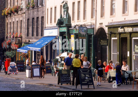 People at sidewalk tables at old pubs along Grassmarket in Edinburgh Scotland Stock Photo