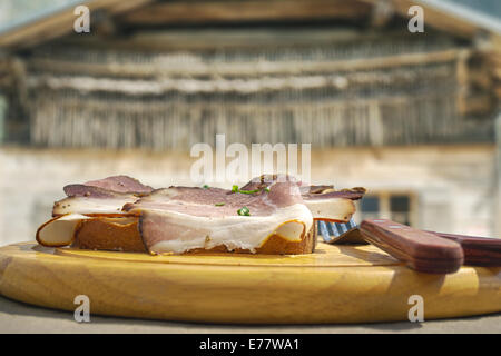 HDR image of cold cuts on wooden plate in front of a mountain hut in the alps Stock Photo