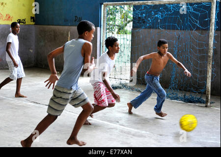 Teenagers playing soccer on a covered sports field, in the slums ...