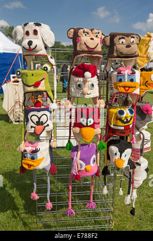 Collection of colourful comical hand crafted knitted hats depicting animals and cartoon characters on stand at market stall Stock Photo
