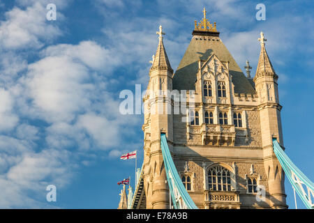 The south tower of Tower Bridge in London, England - in golden evening light. Flags blowing in the wind against blue skies Stock Photo