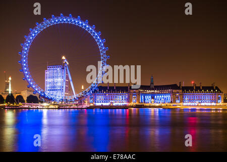 The London Eye, County Hall and Shell Centre buildings at night on the Thames river in London, England. Stock Photo