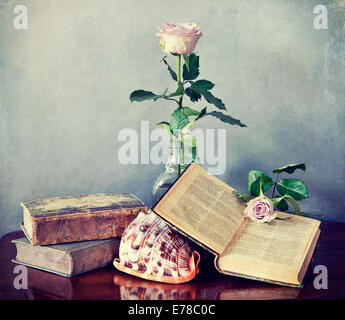 Interior still life, composition of antique books, pink roses and shell with retro desaturated Instagram-like effects Stock Photo