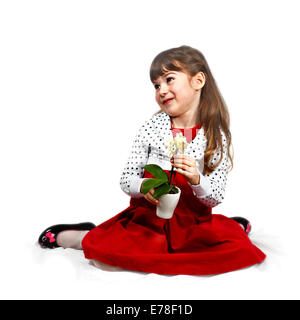 Flirtatious cute girl with orchid in hands dressed in red sits on folded cover. Portrait on white background with light shadows Stock Photo