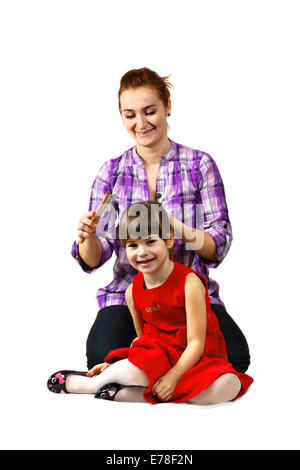 Mother combs her little daughter hair. Portrait  on white background with shadows Stock Photo