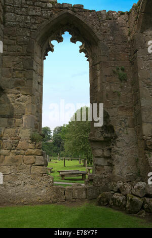 Imposing ruins of historic Bolton Abbey priory with graveyard, blue sky and rural landscape beyond window - Yorkshire England Stock Photo