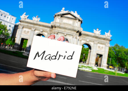 a man holding a signboard with the word Madrid written in it in front of La Puerta de Alcala in Madrid, Spain Stock Photo
