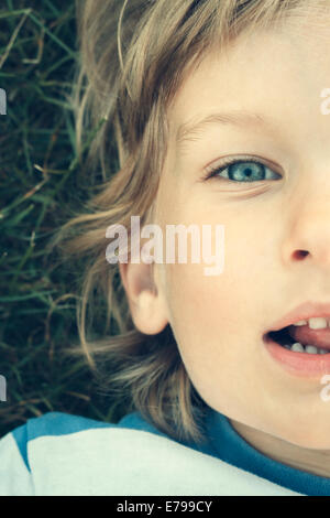 Young boy looking at camera while lying on back. Stock Photo