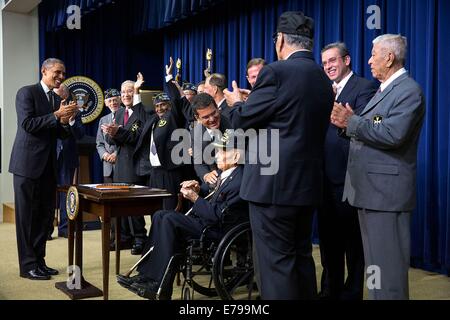 US President Barack Obama applauds after signed H.R. 1726, awarding a Congressional Gold Medal to the 65th Infantry Regiment, known as the Borinqueneers, in the Eisenhower Executive Office Building South Court Auditorium of the White House June 10, 2014 in Washington, DC. Stock Photo