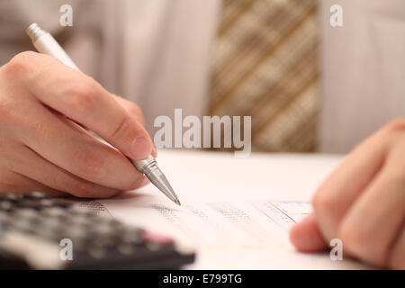 Businessman viewing financial statements. Shallow depth of field. Focus on pen. Close-up. Stock Photo