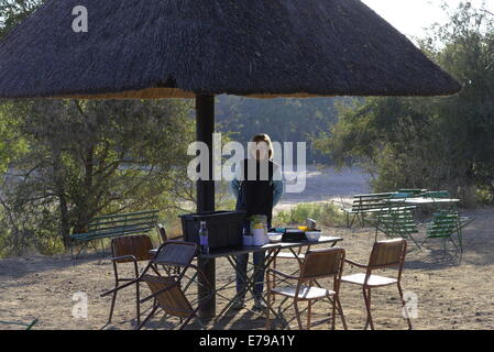 Tourist lady enjoying breakfast at Timbavati picnic spot, Kruger National Park, South Africa. Stock Photo