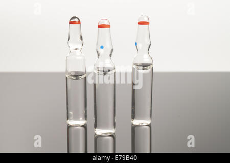 Three Clear medical ampules isolated on black background Stock Photo