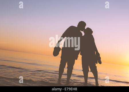 Happy senior couple silhouettes on the beach kissing Stock Photo