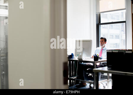 A man seated in an office using a computer. Stock Photo